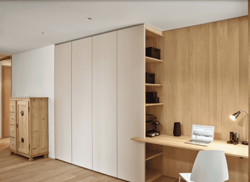 Ein Büro mit maßgefertigtem Einbauschrank in neutralen Farben und integriertem Holzschreibtisch.