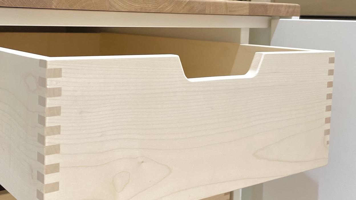 Nahaufnahme einer maßgefertigten Kommode mit offenen Holzschubladen und präzisen Fingerzinken-Verbindungen.