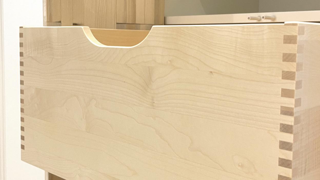 Eine offene Holzschublade mit präziser Fingerzinken-Verbindung in einem maßgefertigten Schrank.