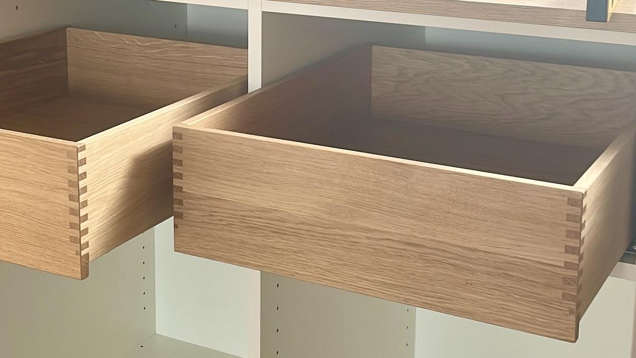 Ein maßgefertigter Schrank unter einer Dachschräge, ausgestattet mit offenen Holzschubladen und einer robusten Arbeitsplatte.