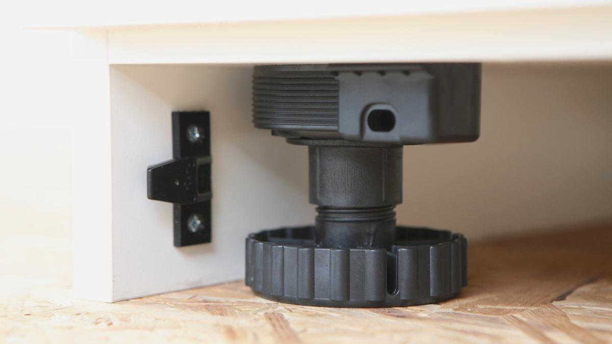 Detailaufnahme eines verstellbaren Sockels Detailaufnahme eines verstellbaren schwarzen Bodensockels mit Schraubmechanismus